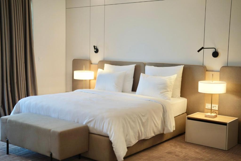 a bedroom with a large white bed with two lamps at Hotel Leone in Međugorje