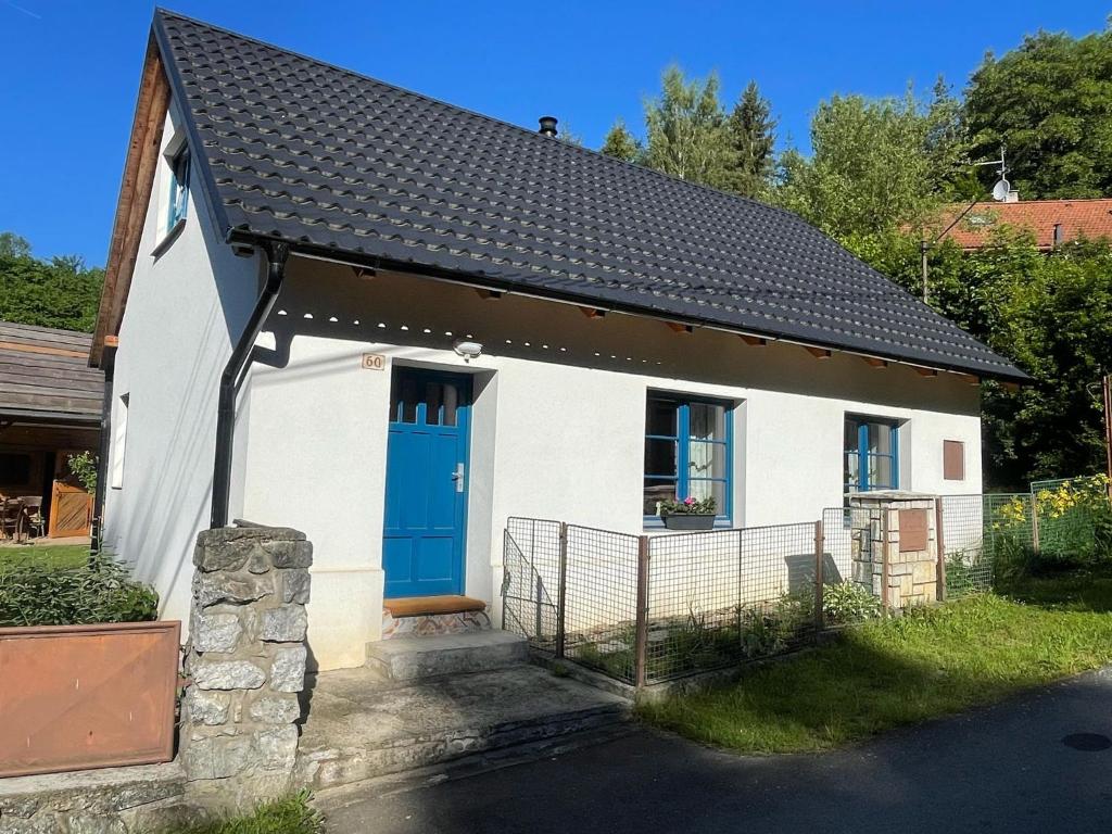 a small white house with a blue door at Chalupa U dančí obory in Hvozd