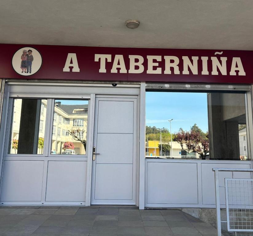 a restaurant with white doors and a sign above it at A Taberniña in O Pedrouzo