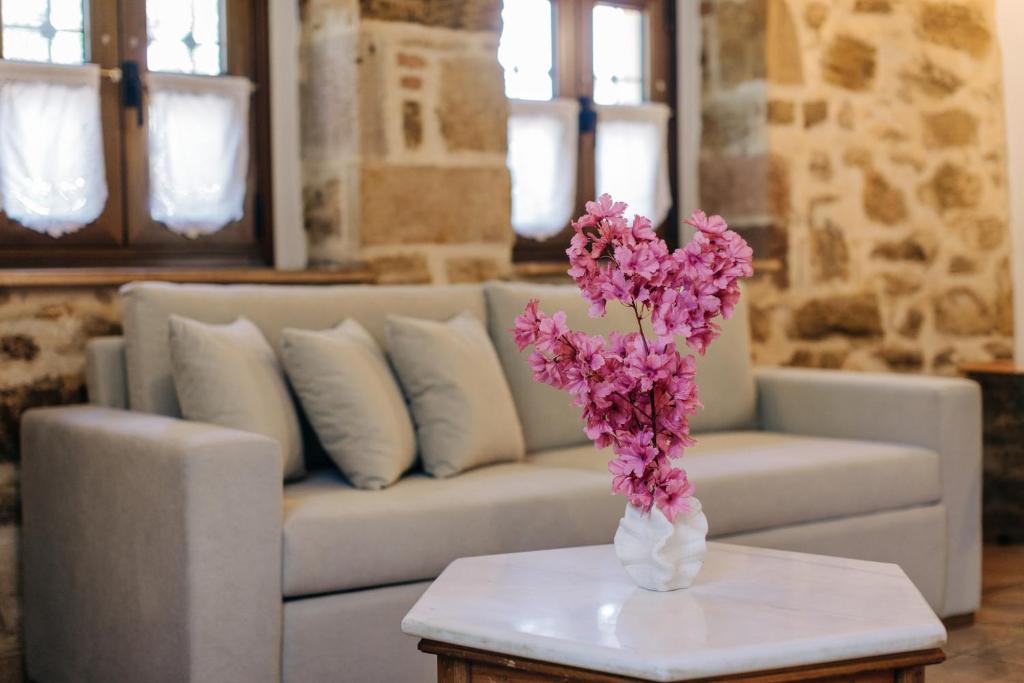 a white vase with pink flowers on a table at Rustic Kampos House Retreat in Chios