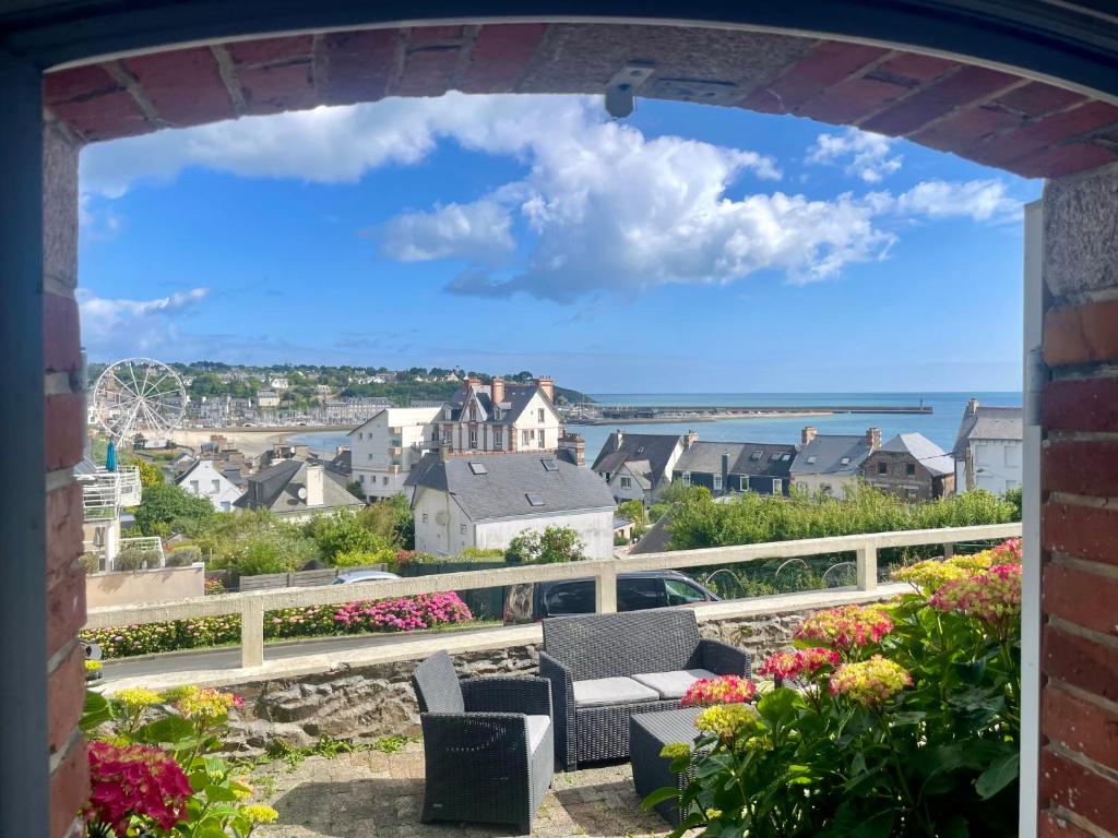a view of a town from an archway with chairs and flowers at logement de charme vue mer in Binic