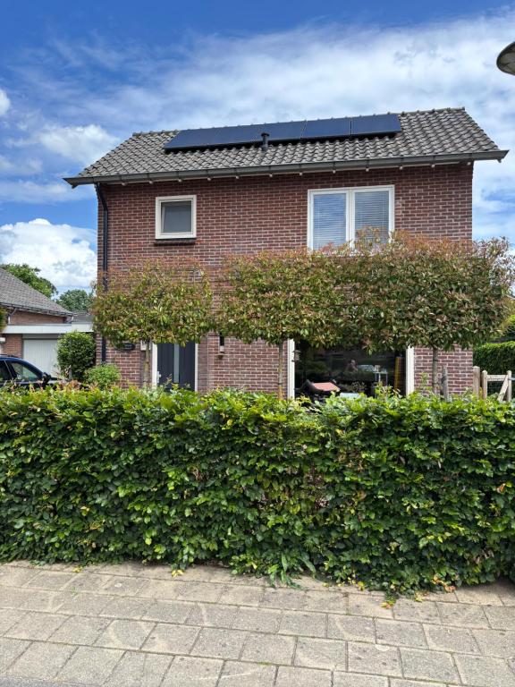a brick house with a hedge in front of it at Bed en Brood Prunushof in Zelhem