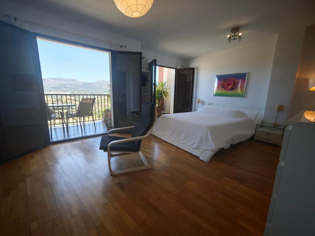 a bedroom with a bed and a chair and a balcony at Vistas de Ronda in Ronda
