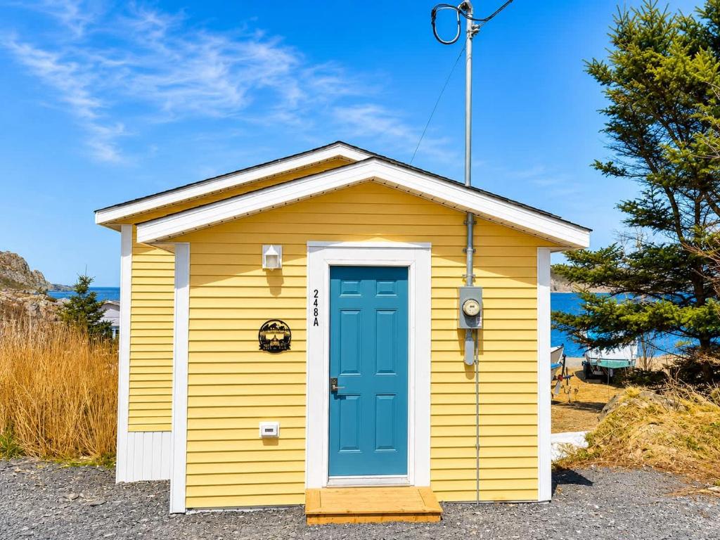 a yellow and blue shed with a blue door at Wild Cove Nook in Twillingate
