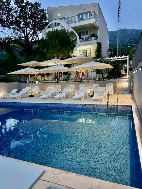 a swimming pool with chairs and umbrellas and a building at Mostoliva Sea View Studios in Pržno