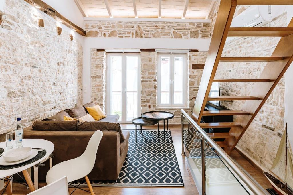 a living room with a couch and a staircase at Alkyoni Samos Maisonette in Mytilinioí