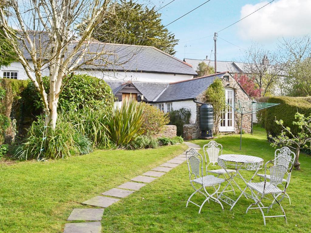 a table and chairs in the yard of a house at The Old Barn in Abbotsham