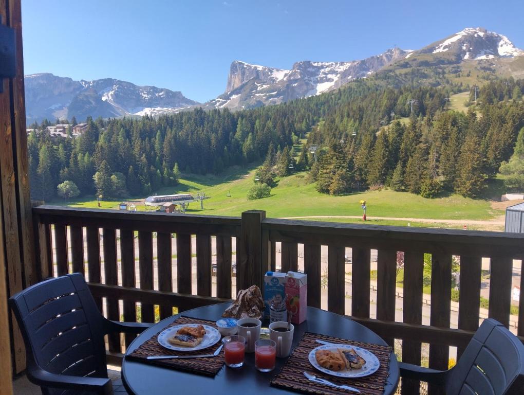a table with plates of food on a balcony with mountains at Appartement avec balcon 6 personnes Superdévoluy in Le Dévoluy