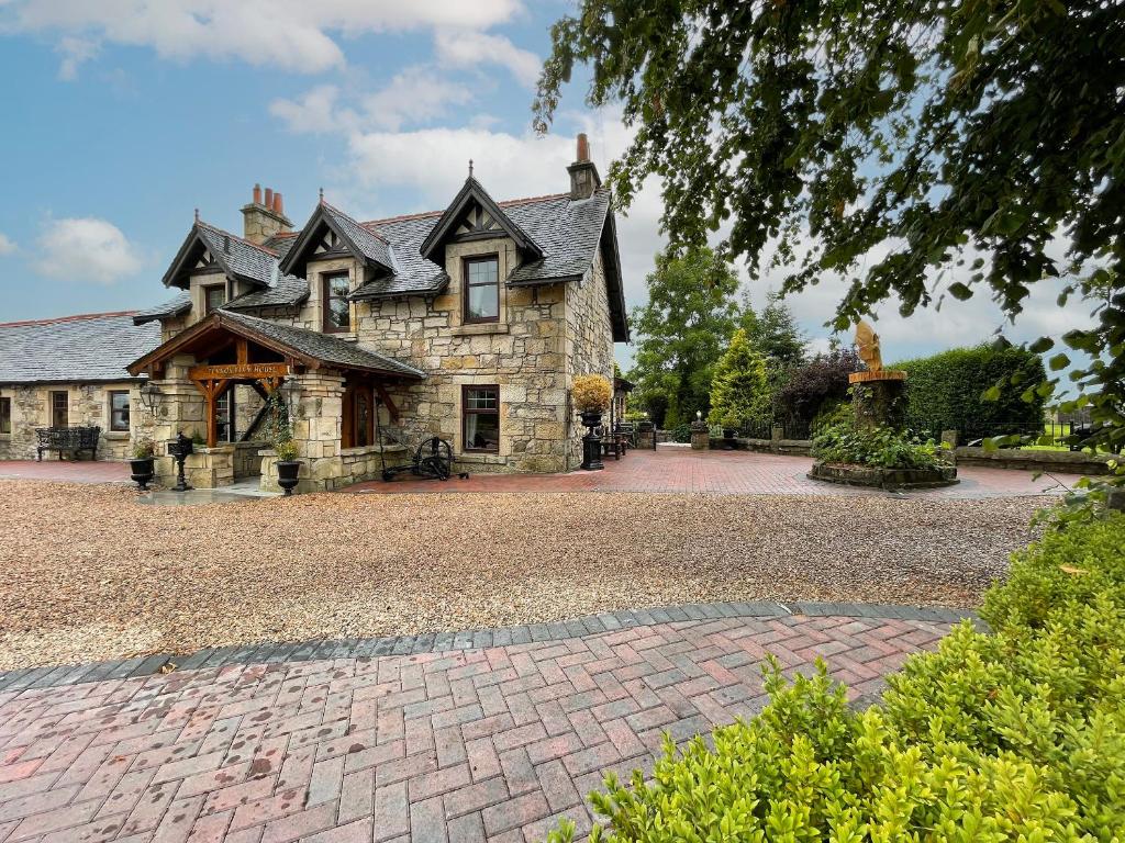 a large stone house on a brick driveway at Tennox Farm House - Uk36254 in Kilbirnie