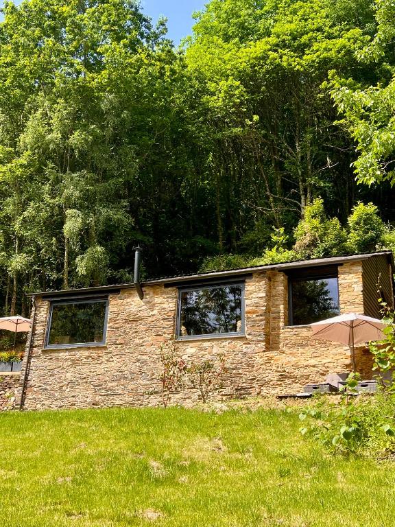 a brick house with two windows and an umbrella at CABAÑA SUITE Deluxe in A Pontenova