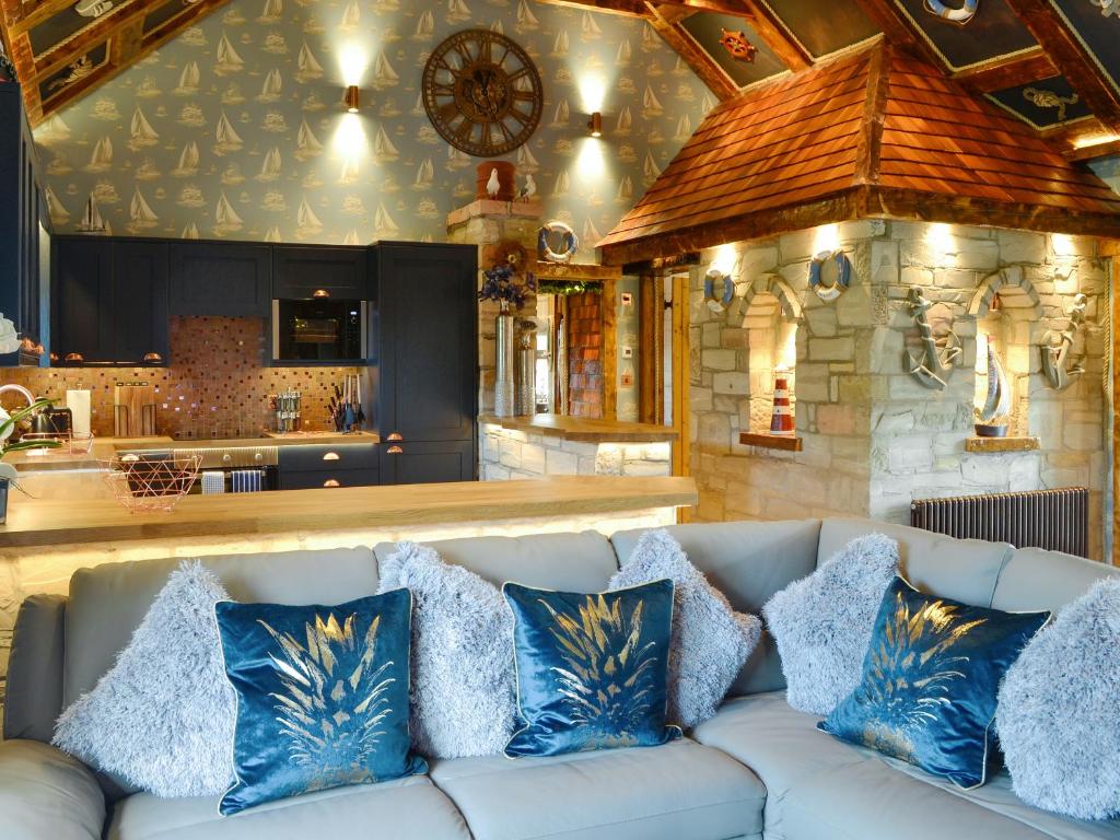 a white couch with blue pillows in a living room at Tennox Boathouse - Ukc4438 in Kilbirnie