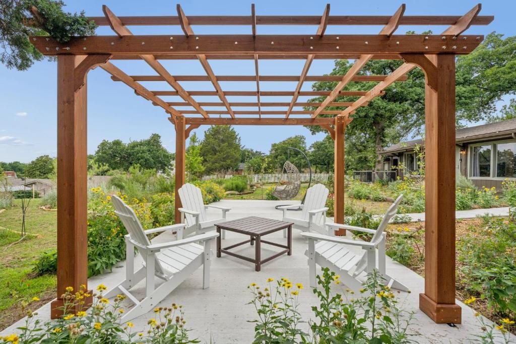a wooden pergola with white chairs and a table at 3BR Cabin Sleeps 10 Fenced Yard in Oklahoma City