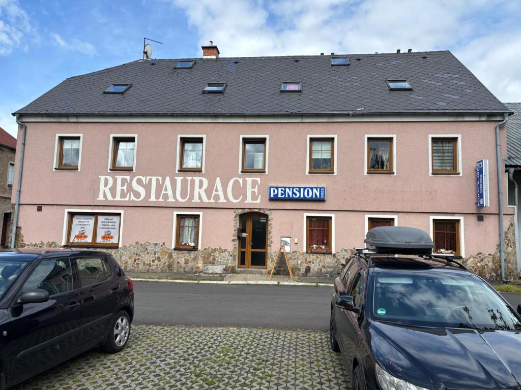 two cars parked in front of a pink building at Penzion Nord in Hora Svatého Šebestiána