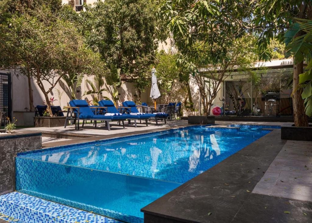 a blue swimming pool with blue chairs and trees at Special offer at 22 by spacey #54 Studio in Maadi in Cairo