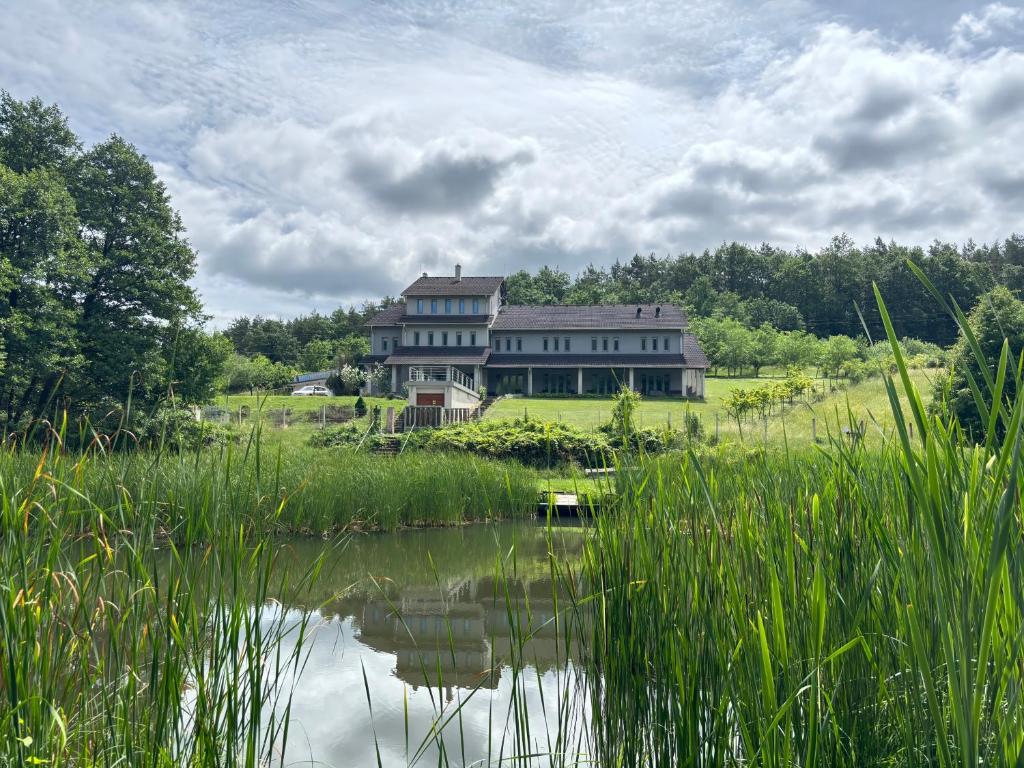 a large house on a hill next to a body of water at Szilva Ház in Szilvásvárad