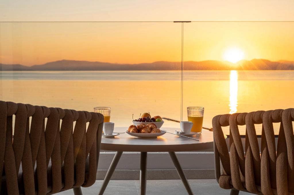 a table with a bowl of food on it with the sunset at Elysian Beachfront Luxury Suite with Jacuzzi - Sea & City View - ADULTS ONLY in Kos