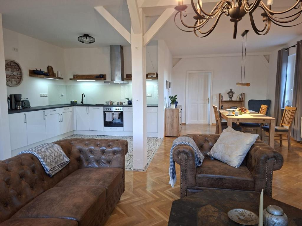 a living room with a couch and a table and a kitchen at Holiday Apartment Henry - Auszeit unter alten Balken in Arnstadt