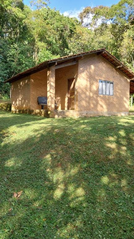 a small brick house in a field of grass at Chácara chalé in Juquitiba