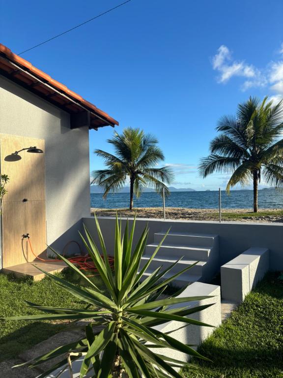 a view of the beach from a house with a palm tree at Espaço Praia - Suíte 101 in Angra dos Reis