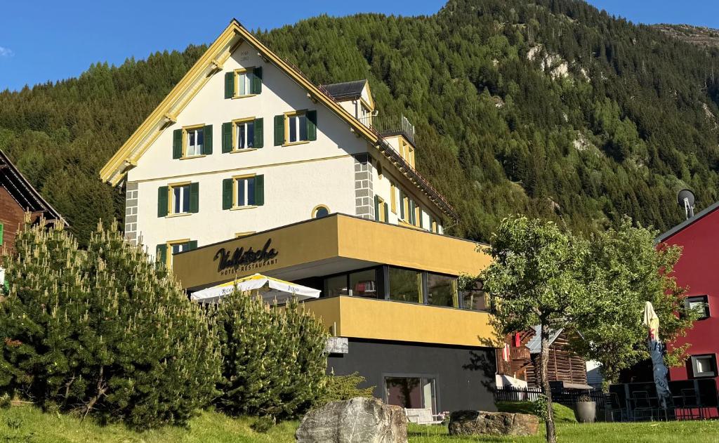 a large building in front of a mountain at Hotel Vallatscha in Curaglia