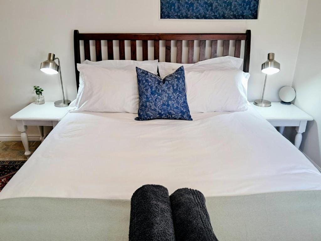 a bed with white sheets and blue pillows at Hope Street Studio in Kuilsrivier