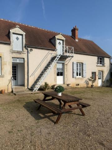 a wooden picnic table in front of a house at La ferme des Gabelles in Saint-Benoît-sur-Loire