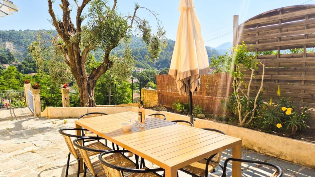 a wooden table and chairs on a patio with an umbrella at Maison Aqua Bella - Terrasse - BBQ - 8pers in Contes