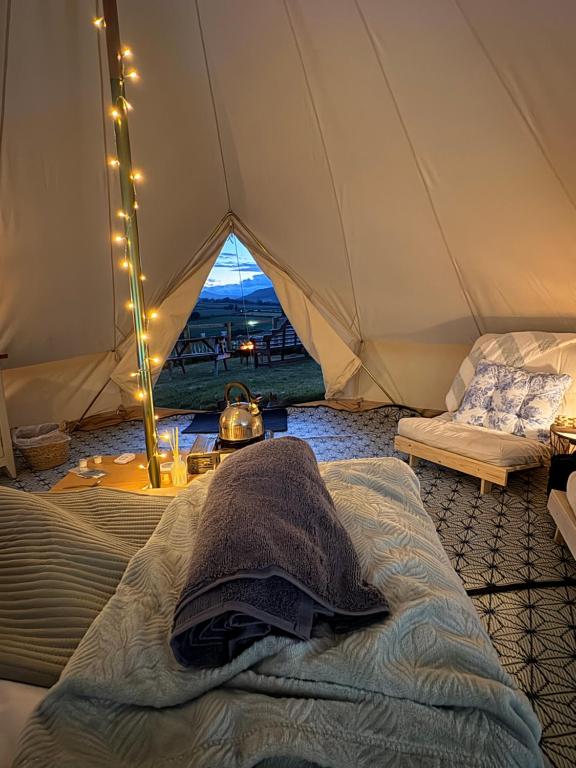 a bedroom with a tent with a bed and a couch at Hedgerow hideaway in Llanvetherine