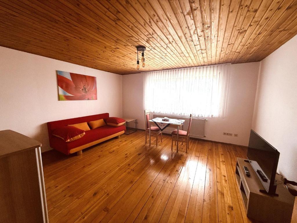 a living room with a red couch and a table at Ferienwohnung Bayerischer Wald in Zwiesel