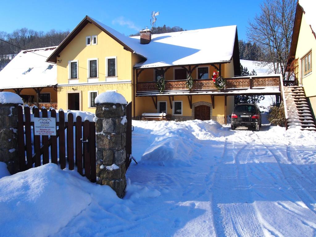 uma casa com uma cerca na neve em Hajduk Apartment em Międzylesie