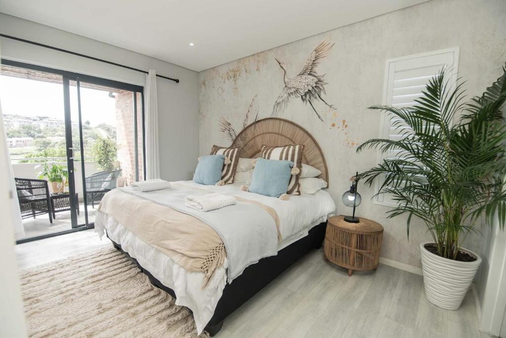 a bedroom with a large bed and a potted plant at Lovemore Retreat in Gqeberha