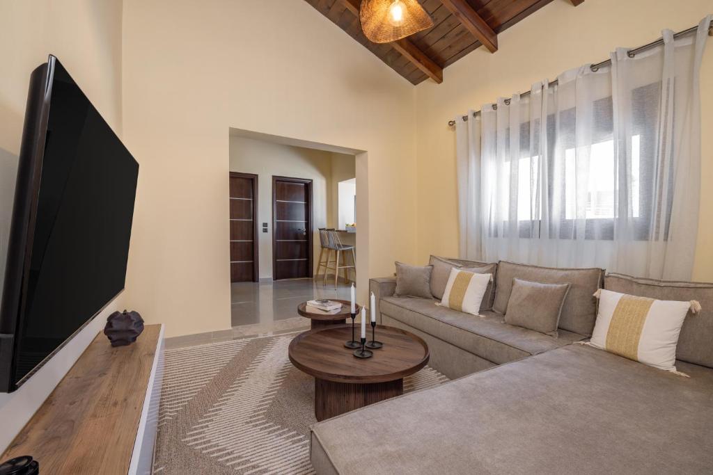 a living room with a couch and a flat screen tv at TheraLiving - Boutique Apartment with Balcony in Afantou