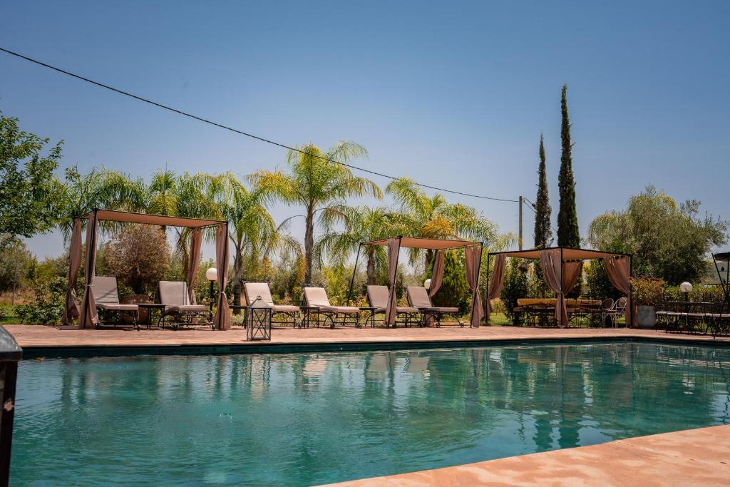 a swimming pool with chaises and chairs next to at Nassau House Marrakech in Mellah Bakka