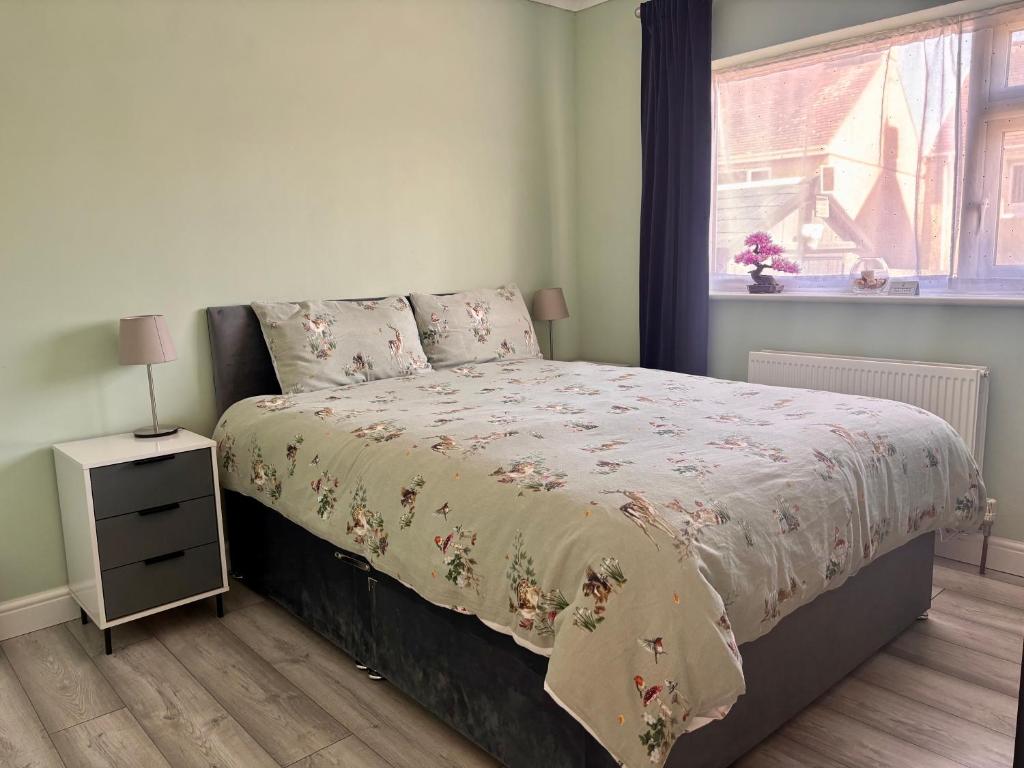 a bedroom with a bed with a night stand and a window at Orient Short Stay in Holyhead