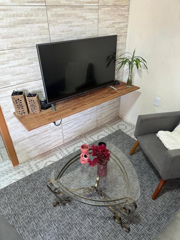 a living room with a television and a table with flowers at Casa Purple House in Urupema