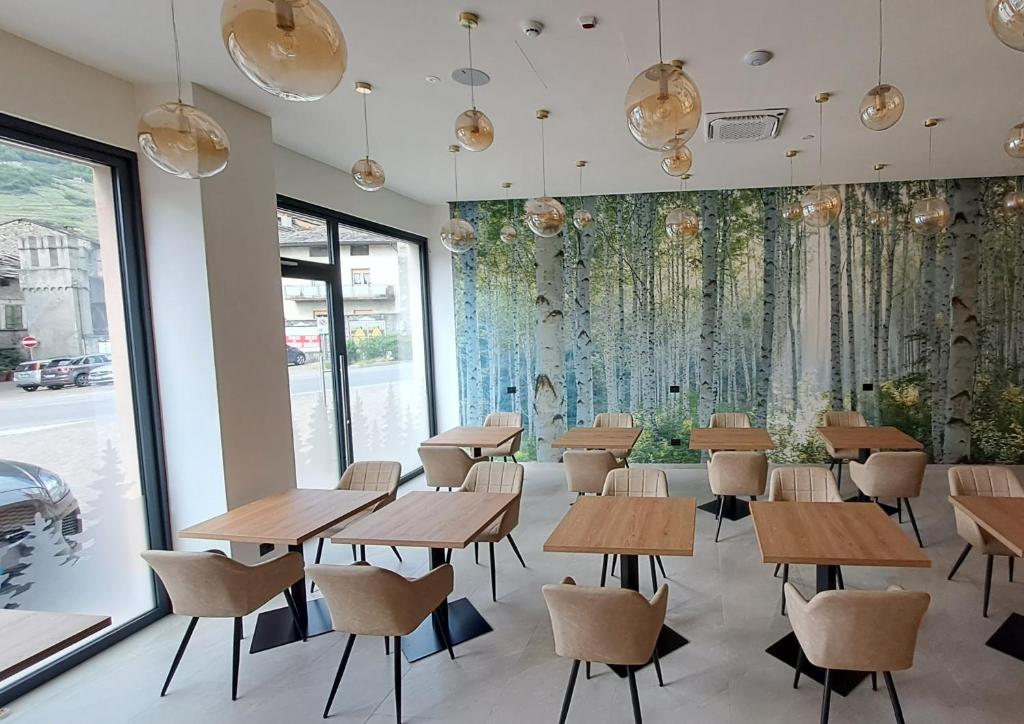 a room with tables and chairs and a wall of windows at MOUNTAIN SUITE Hotel Apartment in Tirano