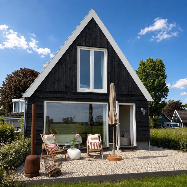 a black house with two chairs and an umbrella at Studio34 in Hauwert