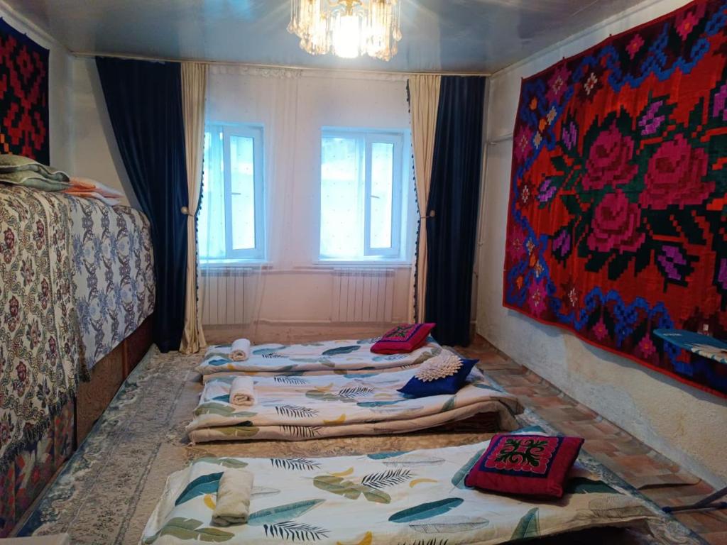 a room with three beds and a painting on the wall at Anarhan Guesthouse Horse riding to Song-Kol and Kilemche in Kyzart