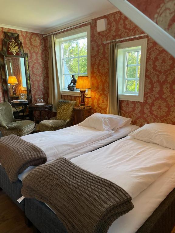 a bedroom with two beds and a chair and windows at Ardrebo B&B in Ljugarn