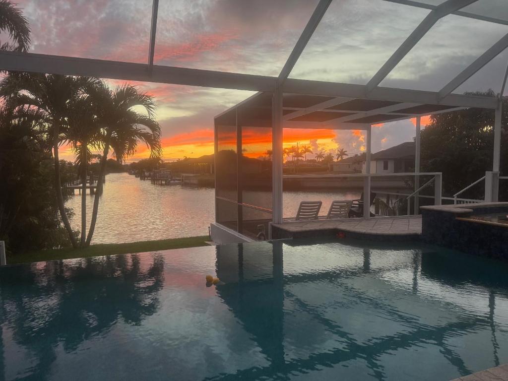 a house with a swimming pool with a sunset at Villa Bremen - Pool / Spa Home in Cape Coral