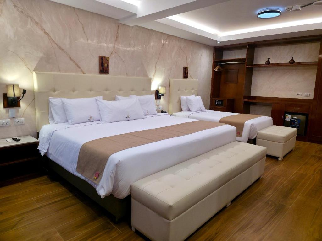 two beds in a hotel room with a large bed at Alpacaterra Machupichu Hotel in Machu Picchu