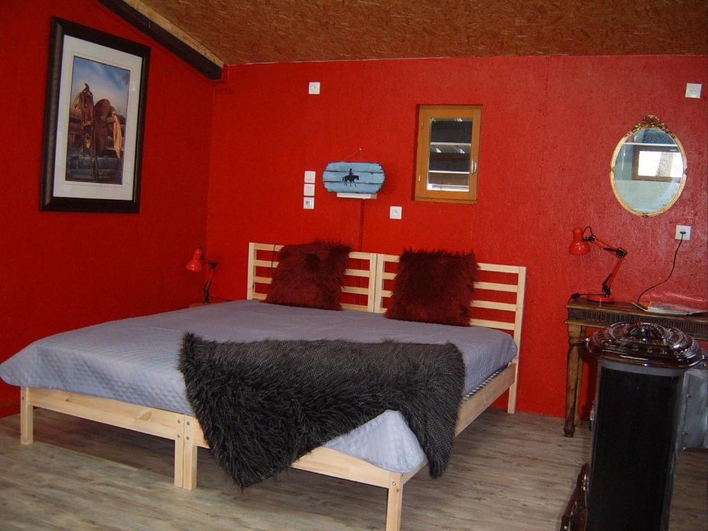 a bedroom with a bed with a red wall at Chalet de campagne LAJA only 5 min from autoroute A75 in Léotoing