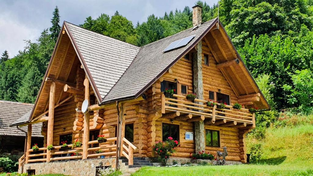 a log cabin with a large gambrel roof at Pensiunea Larix in Răchiţele