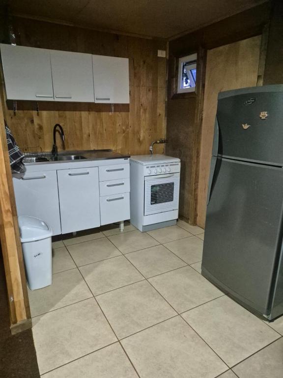 a kitchen with a stainless steel refrigerator and white cabinets at Cabaña Gazul in Porvenir