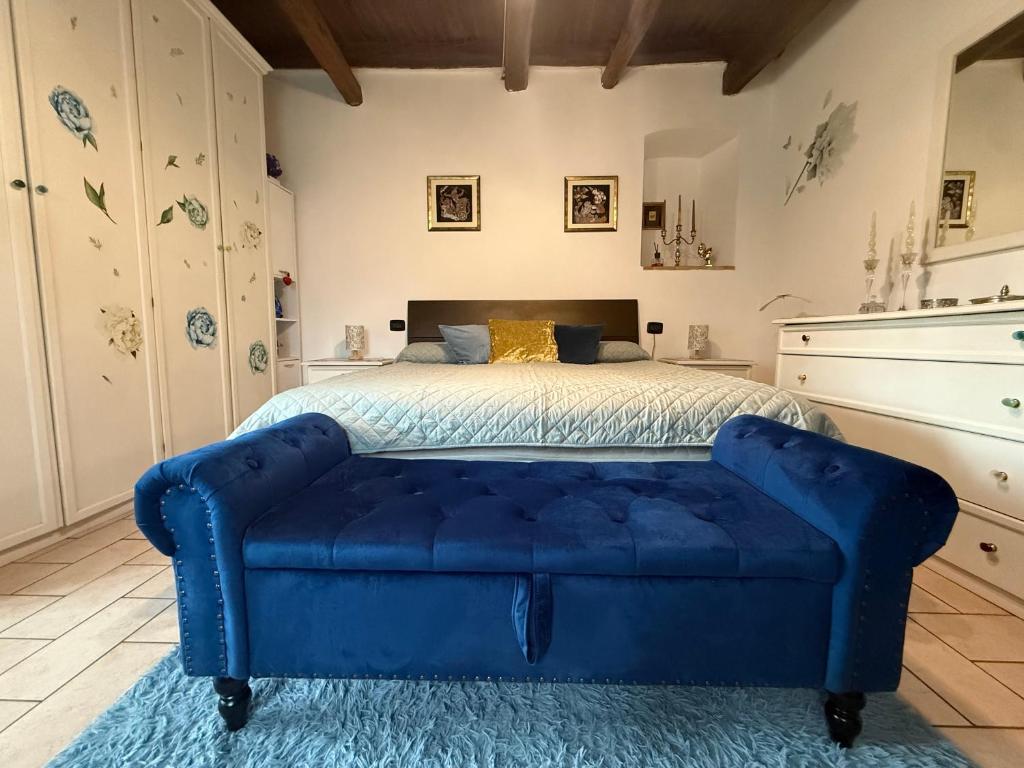 ein blaues, gestepptes Sofa in einem Schlafzimmer mit einem Bett in der Unterkunft Mameli 27 in Spoleto