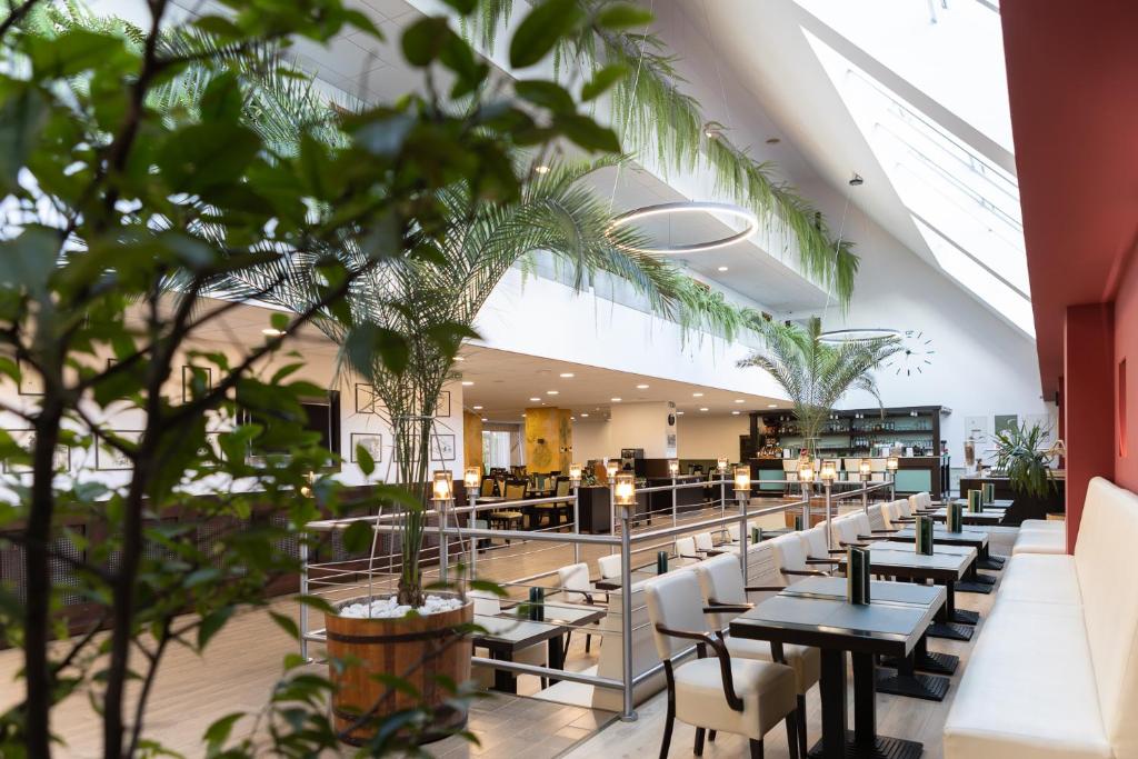 a cafeteria with tables and chairs and plants at Art Hotel superior in Zalakaros