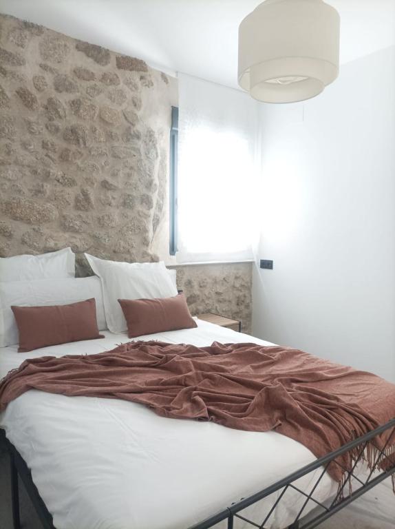 a large bed in a bedroom with a stone wall at El Loft de Cris in Béjar
