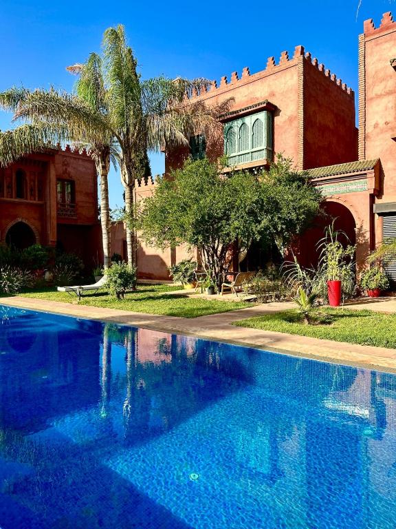 a large blue swimming pool in front of a house at Serene Villa with 4 Pools, Palmeraie, Marrakech in Douar Soukkane