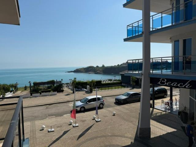 a building with cars parked in a parking lot next to the ocean at ESKADA Apartments in Ahtopol