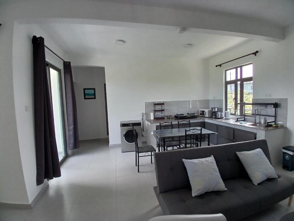 a living room with a couch and a table and a kitchen at Acacia Residences in Post of Flacq